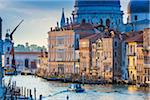 Boat travelling along the Grand Canal with sunlit historical buildings along the shoreline in Venice, Italy