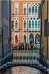 Small bridge crossing a canal looking through to sunlit buildings along along the Grand Canal in Venice, Italy