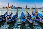 Gondola boats moored along the San Marco canal in Venice with San Giorgio Maggiore and St Mark's Campanile in the distance, Italy