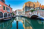 Reflection of the historic buildings in the Rio de Malcanton canal at sunrise with Ponte Marcello on the right in Venice, Italy