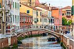 Stone footbridge with iron railing crossing a canal in Venice, Italy