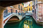Looking through stone footbridges crossing a canal in Venice, Italy