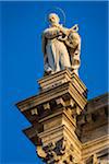 Close-up of a religious statue on the Church of Saint Roch against a blue sky in Venice, Italy