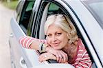 Portrait of mature woman looking out of car window on roadside