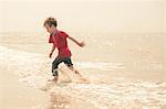Boy running and splashing in sea
