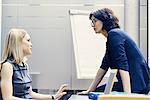 Two businesswomen having discussion at office desk