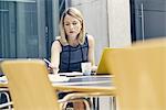 Young businesswoman writing at office desk