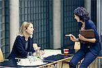 Two businesswomen having discussion at boardroom table