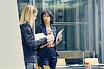 Two businesswomen having discussion in open plan office