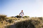 Young man training, power walking on sand dunes
