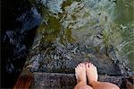 Woman's feet at edge of wooden pier by water