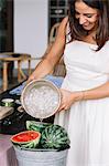 Woman pouring ice water into bucket of watermelon