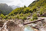 Man crossing waal river on bridge made of pipes, Accursed mountains, Theth, Shkoder, Albania, Europe