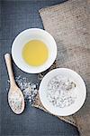 Bowl of oil and salt mixed with herbs, ingredients for home-made body scrub, overhead view