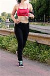 Young female runner running along riverside