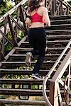 Young female runner running up stairway