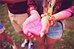 Pink chalk cupped in young woman's hands at festival