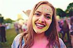 Portrait of young boho woman with face covered in coloured chalk powder at festival