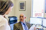 Over shoulder view of manager having discussion with office worker at office desk