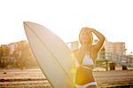 Young female surfer in bikini shielding eyes from sunlight on beach, Santa Monica, California, USA