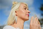 Mid adult woman meditating holding crystal against blue sky