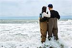 Rear view of young couple in waders sea fishing