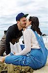 Young woman kissing sea fishing boyfriend on beach