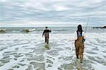 Young sea fishing couple in waders, wading in sea