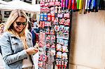 Female tourist, at souvenir stand, choosing souvenirs, smiling