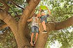 Children sitting in tree using digital tablet