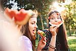 Young boho women making smiley face with melon slice at festival