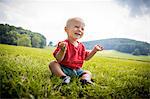 Happy baby boy sitting in rural field