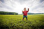 Baby boy toddling in grassy  rural field