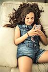 A girl lying down and looking at a mobile phone.