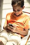 A boy sitting looking at a mobile phone screen.