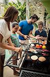 A family standing at a barbecue cooking food.
