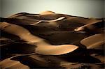 Desert landscape with sand dunes under a clear hazy sky.