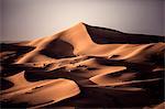Desert landscape with sand dunes under a hazy sky.