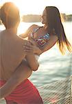 A man holding a young woman and swinging her around on the deck of a boat.