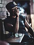 Man sitting at a table in a bar smoking a cigar.