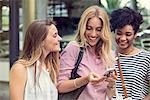 Young woman looking at smartphone and chatting with friends outdoors