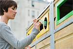 Woman placing plastic bottle in recycling bin