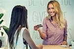 Cashier holding customer's credit card and smiling cheerfully