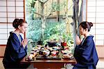 Caucasian woman wearing yukata eating with Japanese friend at traditional ryokan, Tokyo, Japan