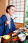 Caucasian woman wearing yukata eating at traditional ryokan, Tokyo, Japan