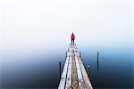 Man standing at the end of wooden pier