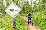 Boy cycling, bear crossing sign on foreground