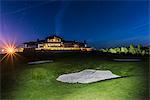 Golf course, illuminated building on background