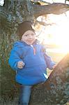 Smiling boy sitting on branch