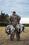 Hunter carrying dead geese